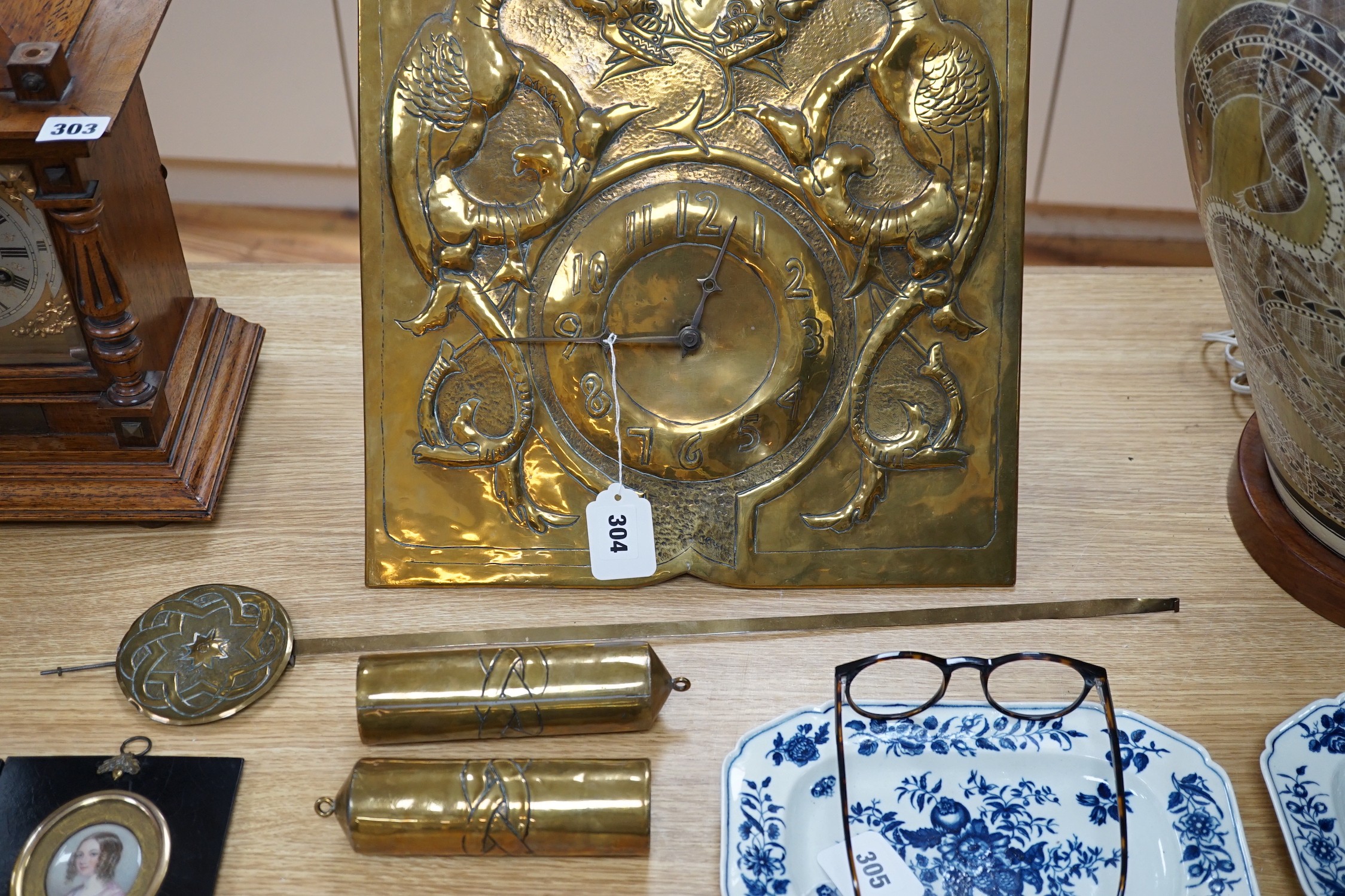 An early 20th Century Arts & Crafts/Art Nouveau brass wall clock in the manner of Margaret Gilmour, Glasgow School with embossed weights and pendulum, dial 37x37cm, Black Forest type movement